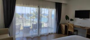 a bedroom with a large window with a view of a resort at Hotel El Quemaito - Luxury Oceanfront Retreat in Santa Cruz de Barahona