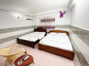Habitación con 2 camas y una silla. en Huy Hoàng Hotel, en Ho Chi Minh