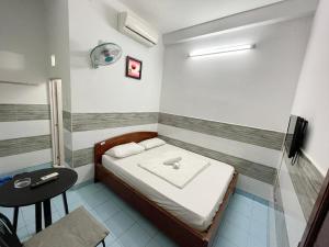 Kleines Zimmer mit einem Bett und einem Tisch in der Unterkunft Huy Hoàng Hotel in Ho-Chi-Minh-Stadt