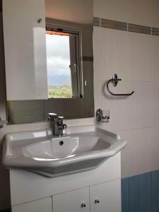 lavabo blanco en el baño con espejo en Kwnstantias Houses 2, en Filiatra
