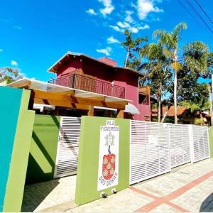 a house behind a white fence with a building at Vila Figueiredo das Donas - Suíte Espaço Gourmet in Bombinhas