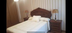 a bedroom with a large bed with a wooden headboard at OKTHEWAY MALPICA in Malpica