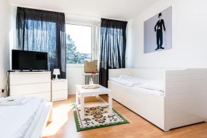 a white bedroom with two beds and a tv at Budget Apartment Köln in Cologne