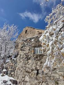 ein Steingebäude mit einem Fenster im Schnee in der Unterkunft Chambre ou gîte dans une maison de montagne - De Suzon à Zélie in Entraigues