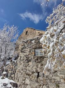 a stone building with a window in the snow at Chambre ou gîte dans une maison de montagne - De Suzon à Zélie in Entraigues