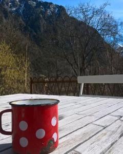 a red polka dot coffee cup sitting on a wooden table at Chambre ou gîte dans une maison de montagne - De Suzon à Zélie in Entraigues