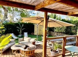 a patio with a couch and an umbrella at Cottage cosy Bassin d'Arcachon in La Teste-de-Buch