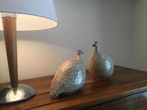 zwei Papiervögel auf einer Kommode neben einer Lampe in der Unterkunft Charmante maison VintageCorner in Saint-Blaise