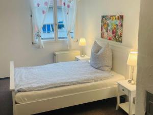 - une chambre avec un lit blanc, 2 tables et 2 fenêtres dans l'établissement Apartment in Meersburg right on the water, à Meersburg