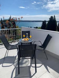 einen Tisch und Stühle auf einem Balkon mit Blick auf das Wasser in der Unterkunft Apartmaji Amitis in Portorož
