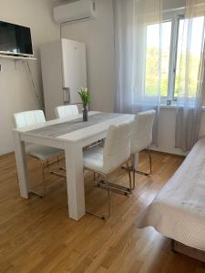 ein weißer Esstisch mit weißen Stühlen im Zimmer in der Unterkunft Apartmaji Amitis in Portorož