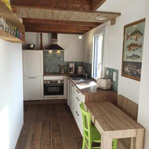 a kitchen with white cabinets and a wooden table at Ty Calouenn, la plage à pied in Le Pouldu