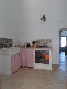 a kitchen with a table and a stove and a sink at Il Trullo Bianco a Masseria Santalachicca in Masseria Orimini
