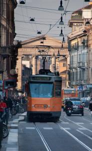 Ein orangefarbener Wagen fährt eine Stadtstraße hinunter in der Unterkunft Easy Milano - Rooms and Apartments Navigli in Mailand