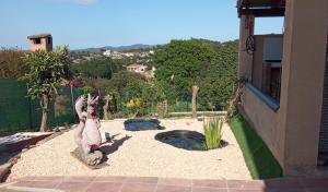 un jardin avec une statue à côté d'une maison dans l'établissement VILLA BLANCA 10 minutos de la Playa Costa brava, à Maçanet de la Selva