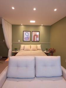 um quarto com uma cama grande e 2 assentos brancos em Residence Farol - Loft 206 em Laguna