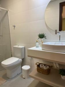 a bathroom with a toilet and a sink and a mirror at Residence Farol - Loft 206 in Laguna