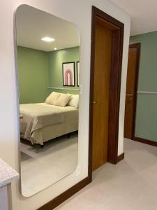 a mirror in front of a bedroom with a bed at Residence Farol - Loft 206 in Laguna