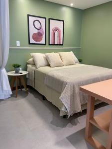 um quarto verde com uma cama e duas mesas em Residence Farol - Loft 206 em Laguna