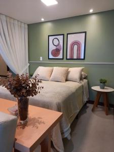 um quarto com uma cama, uma mesa e pinturas em Residence Farol - Loft 206 em Laguna