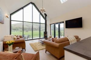 a living room with couches and a flat screen tv at Balbeg Cottage in Straiton