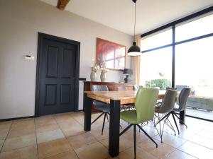 a dining room with a wooden table and green chairs at Modern Saxon farmhouse in Dalerveen village in Dalerveen