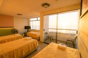 a hotel room with two beds and a balcony at Hotel Huankarute in Huanchaco