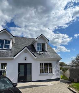 una casa blanca con un coche aparcado en una entrada en 5 Ardaun Monasteraden County Sligo, en Ballaghaderreen