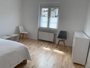 ein Schlafzimmer mit 2 Stühlen, einem Bett und einem Fenster in der Unterkunft Ferienwohnung Diana und Manuel in Weinheim