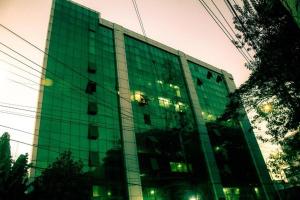 吉大港Hotel Rose Garden的一座高大的绿色玻璃建筑,上面有灯光