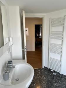 a white sink in a bathroom with a hallway at Argenta Living 2 in Fulda