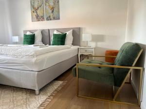 a bedroom with a bed and a green chair at Argenta Living 2 in Fulda