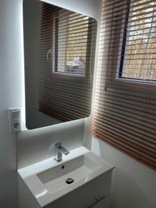 ein weißes Badezimmer mit einem Waschbecken und einem Spiegel in der Unterkunft NEUES Ferienhaus "Kolibri" direkt in Wandlitz, in Wandlitz