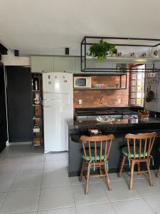 a kitchen with two chairs and a refrigerator at Chalé Serrano in Bananeiras