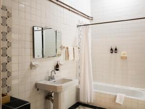 a bathroom with a sink and a tub and a mirror at Agrado Guest House in Oaxaca City