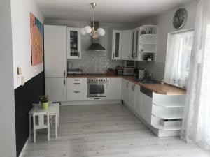 cocina blanca con armarios blancos y mesa en 5 bedroom villa very close to Balaton, en Balatonkenese