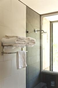 baño con ducha y toallas y ventana en Hotel Casa Zapallar, en Zapallar