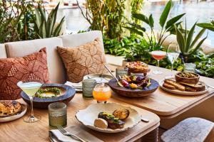 a wooden table topped with plates of food and drinks at Chileno Bay Resort & Residences, Auberge Resorts Collection in Cabo San Lucas