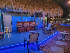 Greenacres City的住宿－Susan and Ledif's Tropical Hideaway，酒吧在晚上在甲板上摆放着凳子和椅子