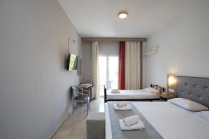 a hotel room with two beds and a television at Silver Bay Hotel Kontokali Corfu in Kontokali