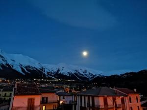 una luna sopra una città con montagne sullo sfondo di PIAZZETTA DEL FORNO GRAZIOSO BILOCALE ad ASSERGI ad Assergi