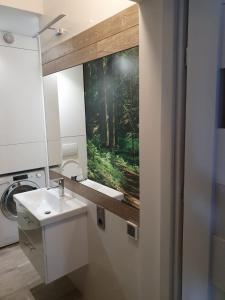 uma casa de banho com um lavatório e uma pintura de uma floresta em Apartament Hania em Tykocin