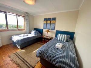 a bedroom with two beds and a window at Charlotte at Paradise Beach in Jeffreys Bay