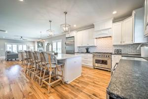 a kitchen with white cabinets and a island with bar stools at Bright Coastal Abode with Porch and Beach Access! in Carolina Beach