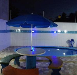 a table with an umbrella in front of a pool at Aconchego in Maragogi