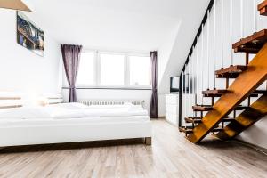 a white bedroom with a bed and a staircase at Budget Apartment Köln in Cologne
