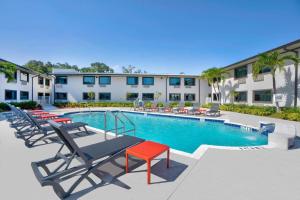 une piscine avec des chaises longues et un hôtel dans l'établissement Motel 6-Fort Lauderdale, FL, à Fort Lauderdale
