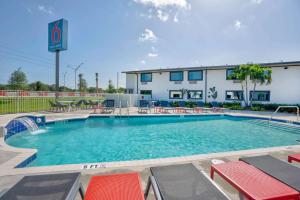 Motel 6-Fort Lauderdale, FL في فورت لاودردال: مسبح وكراسي وطاولات ومبنى