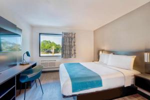 Cette chambre comprend un lit, un bureau et une fenêtre. dans l'établissement Motel 6-Fort Lauderdale, FL, à Fort Lauderdale