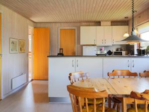 a kitchen with a wooden table and a dining room at Holiday home Dannemare XXX in Dannemare
